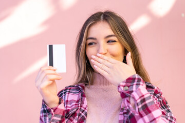 Fototapeta premium Young pretty Romanian woman holding a credit card at outdoors