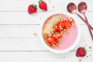 Healthy strawberry and banana smoothie bowl with granola. Overhead view table scene on a white wood background. Copy space. - 759896294