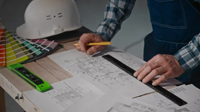 A man uses a ruler to measure the drawing on the table
