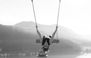 Woman on a Swing with Mountain View and Sunlight over Lake Lugano in Morcote, Ticino in Switzerland.