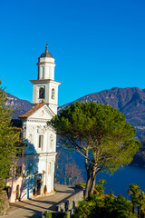 Fototapeta na wymiar Church of Saints Fedele and Simone and Lake Lugano with Mountain in a Sunny Day in Vico Morcote, Ticino in Switzerland.