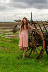 pretty young woman in a pink dress in front of a horse drawn carriage
