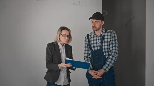 Conflict at a construction site. A woman is a customer, arguing with a builder contractor. The client is not satisfied with the construction work