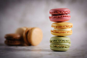 Close up of 3 vividly colored stacked macaroons against a light background with some brown toned...