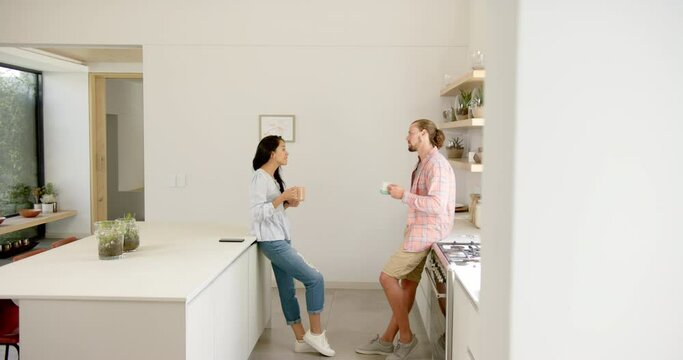 A diverse couple enjoys a conversation in a modern kitchen at home