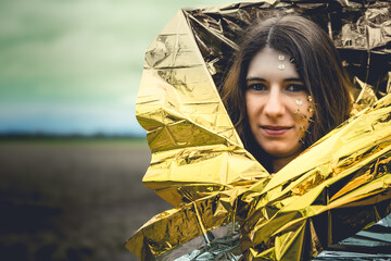 woman as a fantasy representation with tacks in her face and a golden rescue blanket