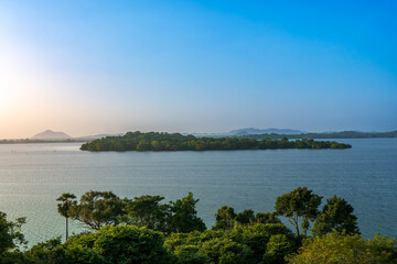 A captivating view of a tranquil lake surrounded by lush greenery, under a clear blue sky, captured at the Heritance Kandalama, Sri Lanka.