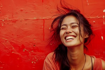 Fototapeta premium Joyful Woman Laughing Against Red Background