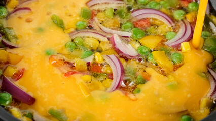 Process cooking frying omelette with vegetables in pan, close up