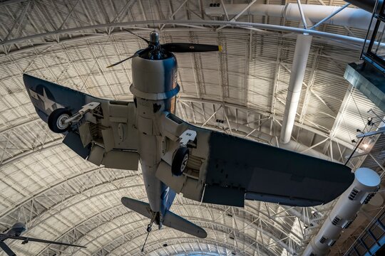 A vintage Vought F4U-1D Corsair fighter aircraft hangs from the ceiling at the Steven F. Udvar-Hazy Center, part of the National Air and Space Museum.
