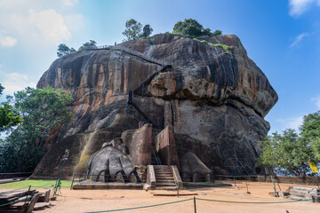 Tourists prepare to ascend the top of Sigiriya Rock, holding onto the railing, with a panoramic view of the site. Dambulla, Sri Lanka.