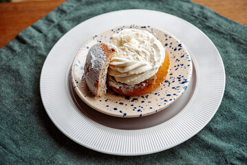 Typical Swedish semla with sweet cream on te blue textile