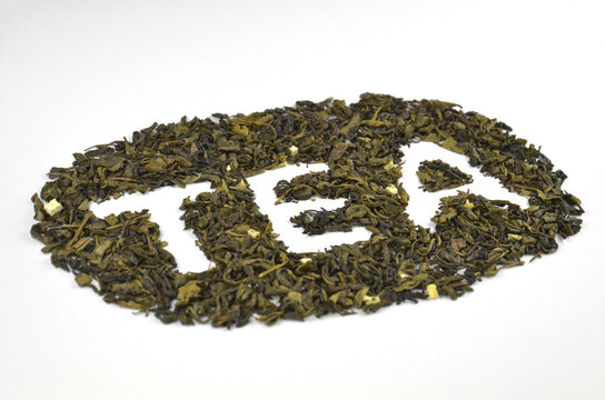 Dry green leaf tea shaped into inscription (text) "TEA", closeup (macro), side view