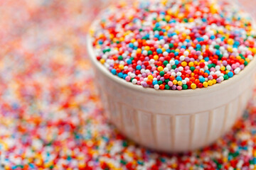 Confectionery sprinkles in bowl. Colorful background. Decoration for cake and bakery.
