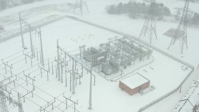 Electrical substation or electric grid of high voltage power lines and wires at winter snow storm. Energy transmission and distribution to the city and households. Electro infrastructure development.