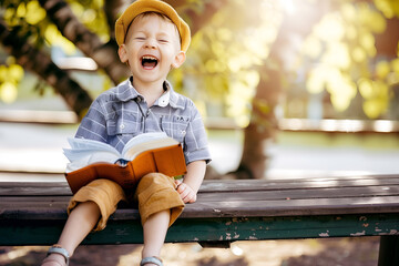 Cute little boy reading holy bible book at countryside - obrazy, fototapety, plakaty