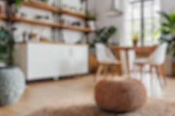 Fototapeta na wymiar Blurred view of modern living room with sofa and soft bench. room interior with couch, armchair and coffee table or shelving units. stylish living room. comfortable workplace near big window. 