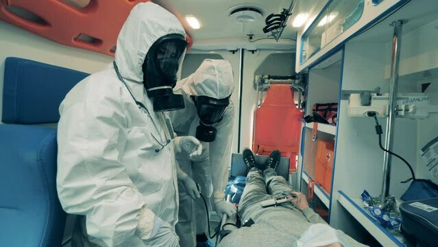Ambulance doctors in hazmat suits are checking up on a patient
