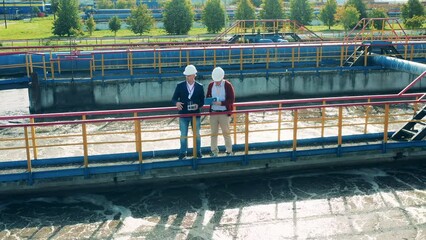 Sewage treatment concept. Businessmen discussing a big sewage cleaning facility