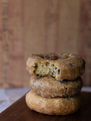 Close up of stack of donuts with a bite taken from one.