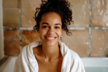 A biracial woman stands in a bathroom, smiling at the camera while wearing a white bathrobe - Powered by Adobe