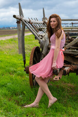 pretty young woman in a pink dress in front of a horse drawn carriage