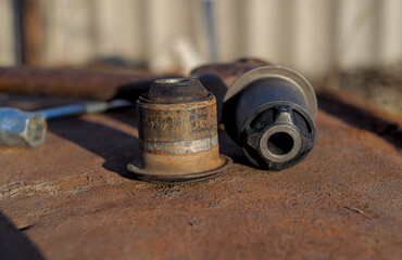 New and used arm bushing on rusty metal.