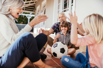 Grandparents and grandchildren having fun with a soccer ball on house porch