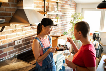 Lesbian couple eating sushi together after moving in