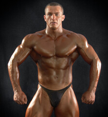 Portrait of a muscular male bodybuilder on a dark background.