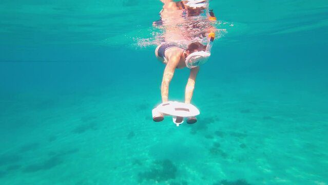 Woman using underwater scooter for diving. Modern sea scooter, modern technology concept.
