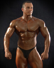 Fototapeta na wymiar Portrait of a muscular male bodybuilder on a dark background.
