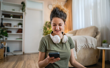 One woman sit on the floor at home with headphones and smartphone