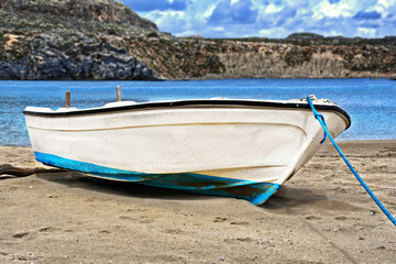 A boat white on the seashore and the sea in the background