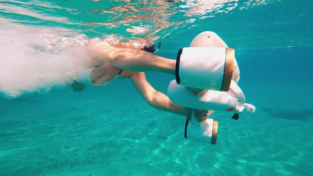 Woman using underwater scooter for diving. Modern technology concept.