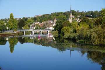 Obraz premium mirror reflection of the bridge, village and forest in the river in eastern france