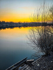 Sunset over the river and red sun . Trees on beach . Reflactions on water. Grass and trees . Red sunset . Sun and forest 