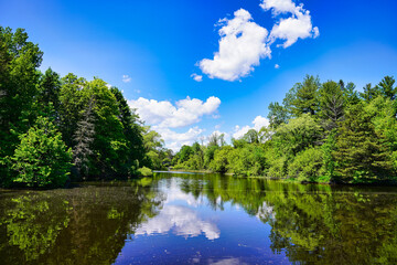 Bright Summer day with greenery,trees and fluffy clouds in a blue sky reflected in the waters of the rideau canal at Ottawa,Ontario,Canada