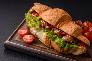 Delicious fresh crispy croissant with chicken or beef meat, lettuce, tomatoes, spices and sauce