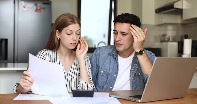 Young Latin couple feel concerned about budgeting while calculating outgoings, lack of money to pay utility bill, facing financial strain due to unexpected expenses, decrease in income or overspending