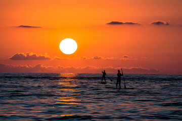 People boating in the sea at a beautiful red sunset