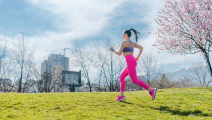 Sportive girl running in park on spring day in front of blossom - 760058809