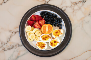 Fresh and healthy breakfast: Hard boiled eggs with banana, orange, strawberry and blue berries.
