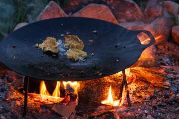 Panierte Fischfilets in der Feuerpfanne über offenem Feuer, Outdoor Küche
