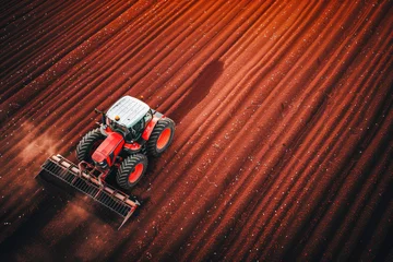 Foto op Plexiglas A tractor tilling the soil, creating precise patterns on the vast farmland, readying the earth for sowing. © Александр Марченко