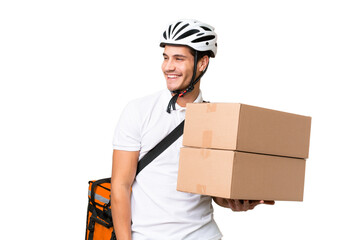 Delivery man wearing a helmet bike over isolated background looking to the side and smiling