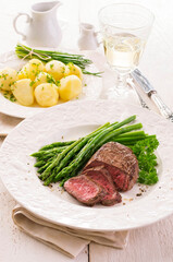 Traditional roasted angus beef steak with green asparagus and boild potatoes served as close-up on a classic plate