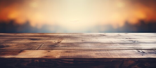 A wooden table sits empty against the backdrop of a stunning sunset. The vibrant colors of the sky merge into the horizon, creating a picturesque evening landscape
