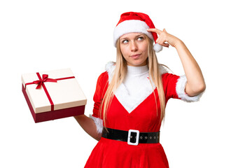 Young blonde woman with christmas hat and holding a gift over isolated chroma key background having...
