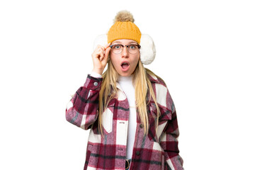 Young pretty blonde woman wearing winter muffs over isolated chroma key background with glasses and surprised